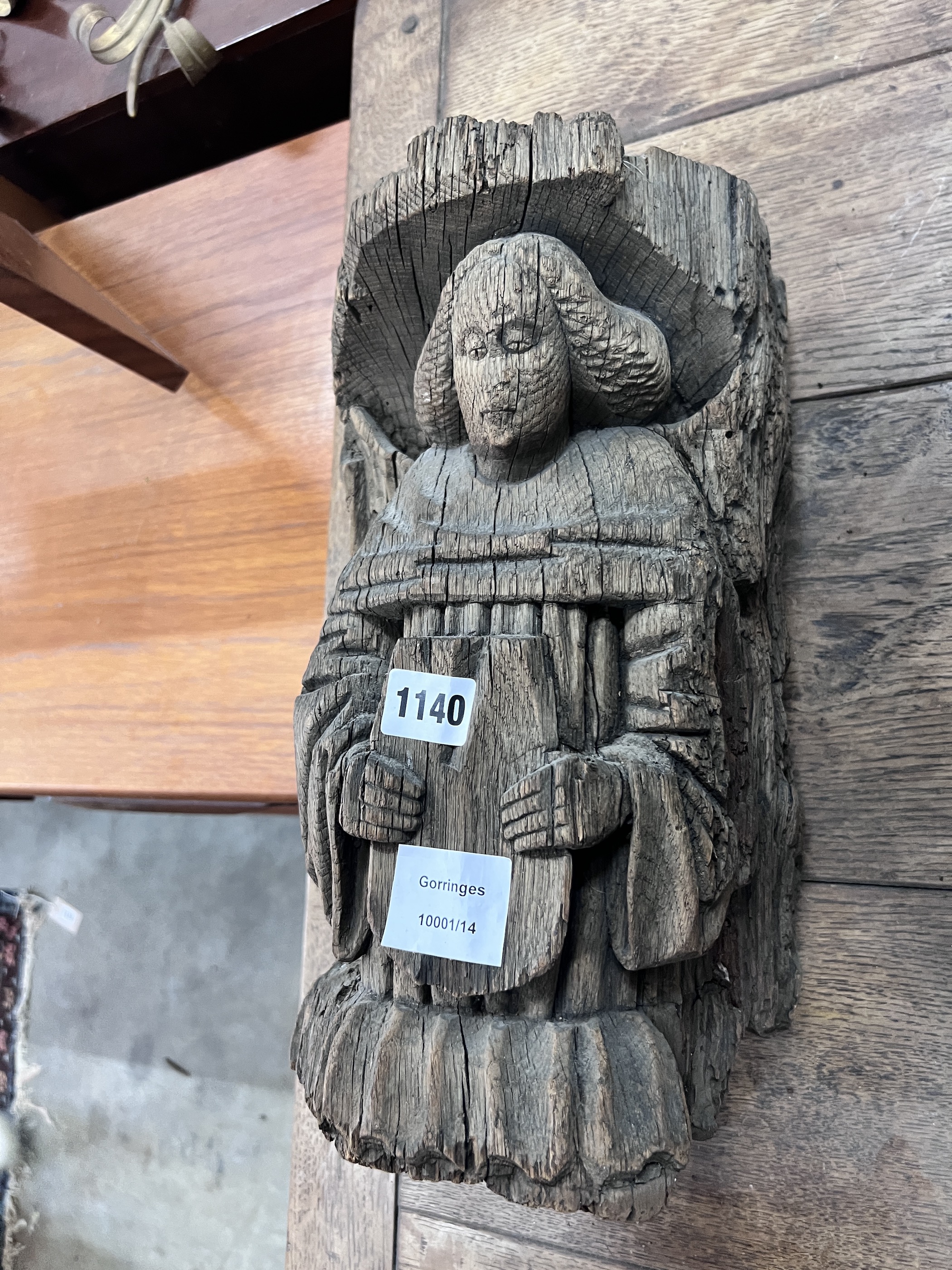 A late 16th carved pine misericord, modelled as a bishop holding a plaque, height 36cm